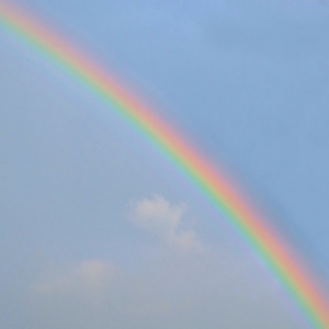 Calm, joyful rainbow reaching across sky