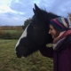 Delia standing next to horse in field and stroking head